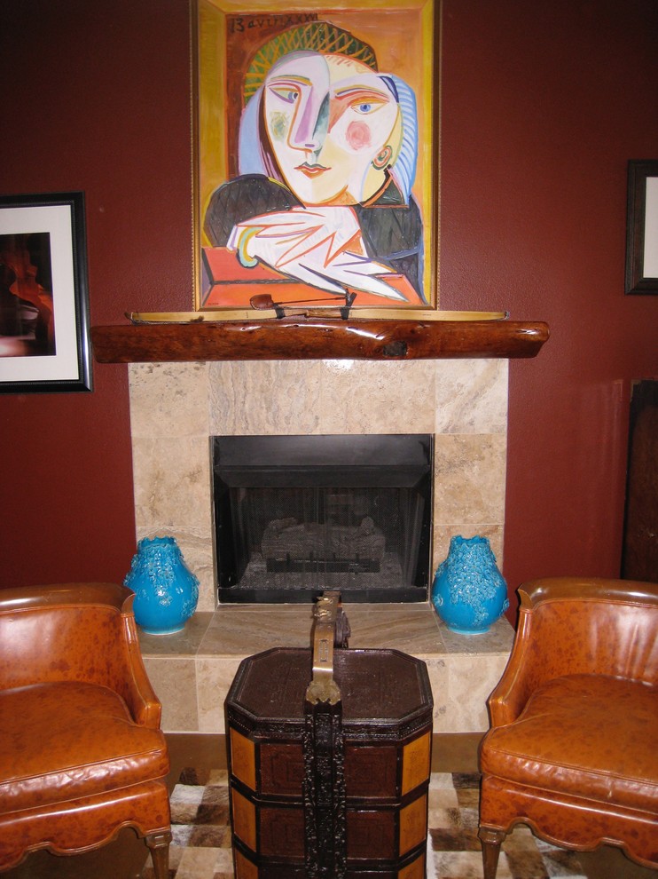 Modelo de despacho ecléctico de tamaño medio con paredes rojas, suelo de madera en tonos medios, chimenea de doble cara, marco de chimenea de piedra y escritorio empotrado