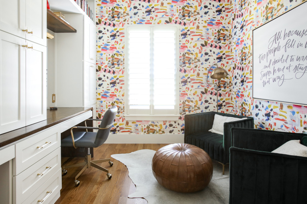 Cette image montre un bureau traditionnel de taille moyenne avec un sol en bois brun, un bureau intégré, du papier peint, un mur multicolore et un sol marron.
