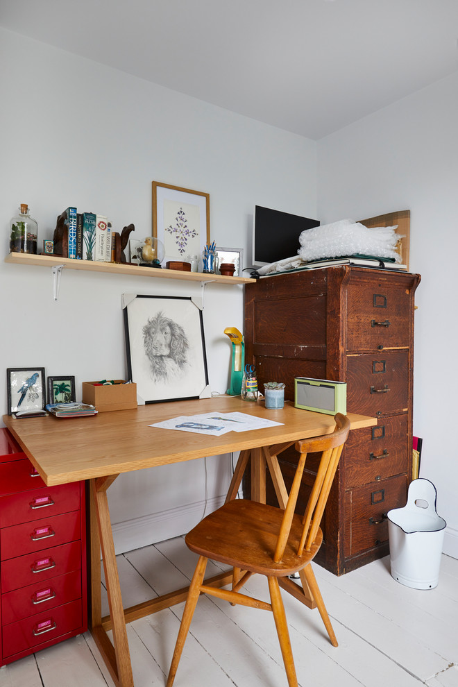 Foto på ett eklektiskt hemmabibliotek, med vita väggar, målat trägolv, ett fristående skrivbord och vitt golv