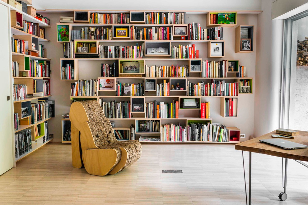 Aménagement d'un grand bureau éclectique avec une bibliothèque ou un coin lecture, un mur blanc, parquet clair et aucune cheminée.