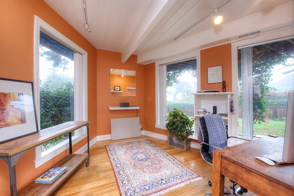 Idéer för att renovera ett litet eklektiskt hemmabibliotek, med orange väggar, ljust trägolv och ett fristående skrivbord