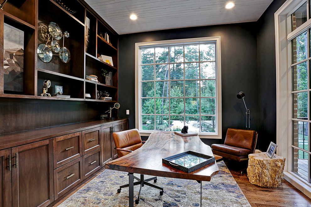 Réalisation d'un grand bureau champêtre avec un mur noir, un sol en bois brun, un bureau indépendant et un sol marron.