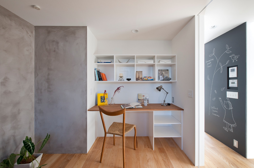Nordisches Arbeitszimmer mit bunten Wänden, braunem Holzboden, Einbau-Schreibtisch und braunem Boden in Sonstige