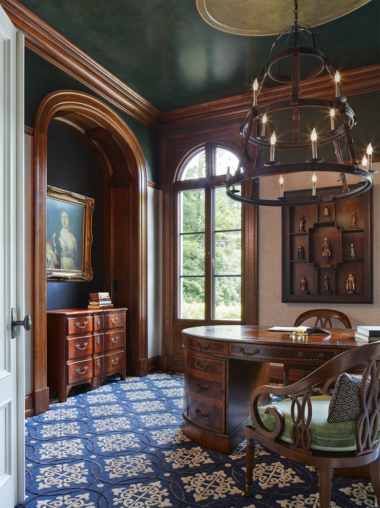 На фото: домашняя библиотека среднего размера в классическом стиле с ковровым покрытием, отдельно стоящим рабочим столом, синим полом и серыми стенами без камина с