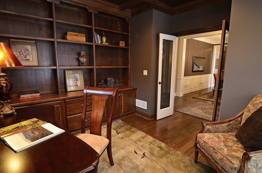 Cette image montre un bureau traditionnel de taille moyenne avec un mur gris, parquet foncé, aucune cheminée, un bureau indépendant et un sol marron.