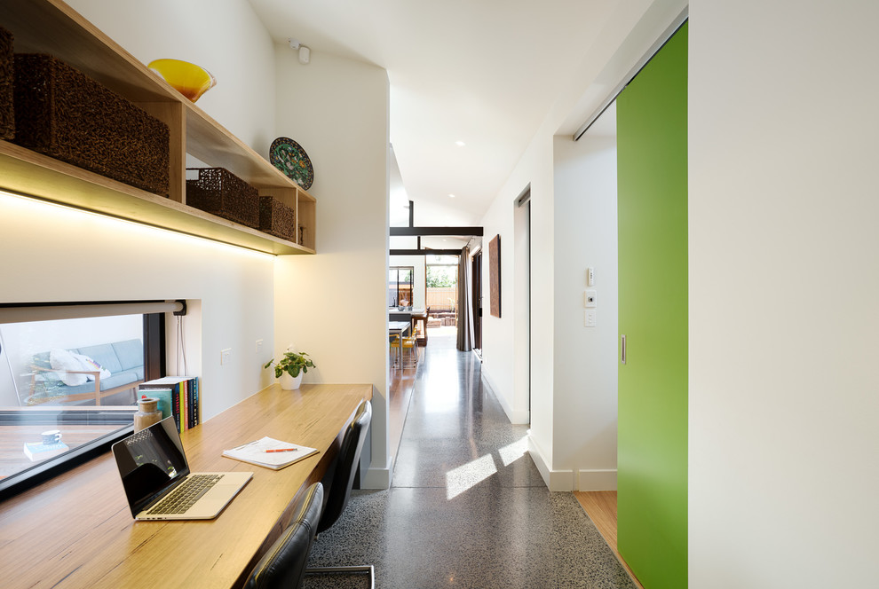 Foto di un ufficio minimalista con pavimento in cemento e scrivania incassata
