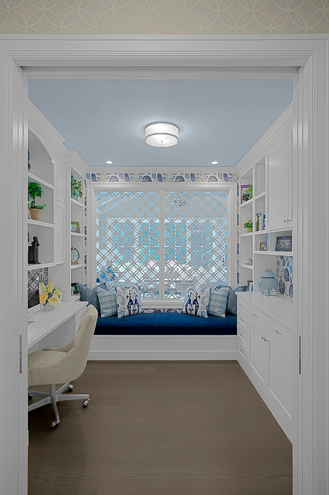 グランドラピッズにあるラグジュアリーな中くらいなトラディショナルスタイルのおしゃれな書斎 (白い壁、無垢フローリング、造り付け机、茶色い床、壁紙) の写真