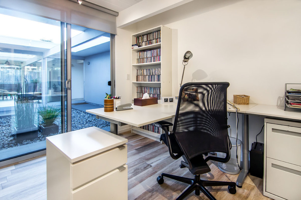 Cette image montre un bureau minimaliste de taille moyenne avec un mur blanc, parquet clair et aucune cheminée.