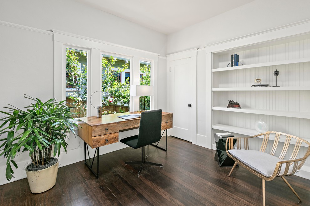 Klassisches Arbeitszimmer ohne Kamin mit Arbeitsplatz, weißer Wandfarbe, dunklem Holzboden, freistehendem Schreibtisch und braunem Boden in San Francisco