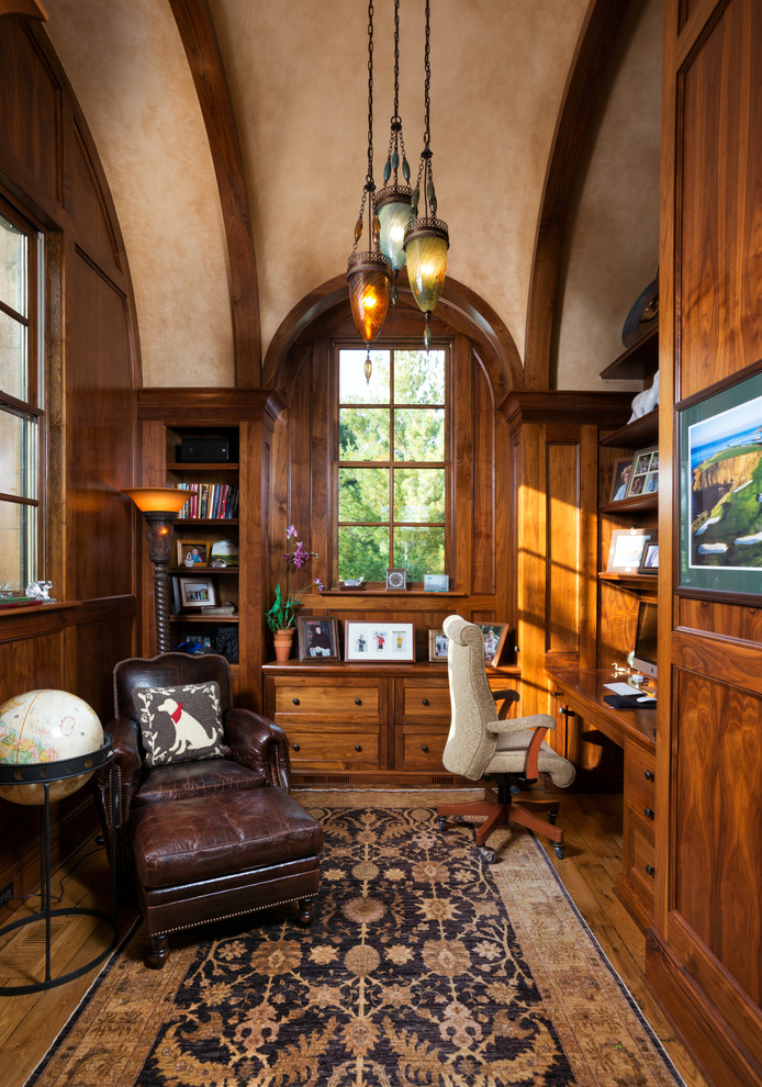 Ejemplo de despacho tradicional de tamaño medio sin chimenea con escritorio empotrado, biblioteca, paredes beige y suelo de madera en tonos medios