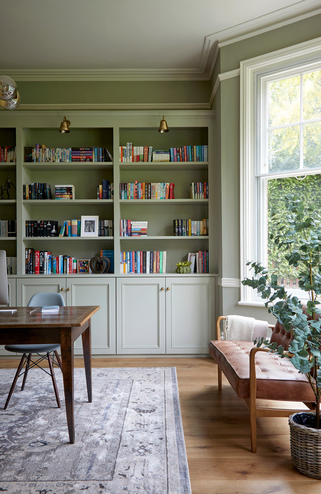Klassisches Arbeitszimmer mit grüner Wandfarbe, braunem Holzboden, freistehendem Schreibtisch und braunem Boden in Hertfordshire