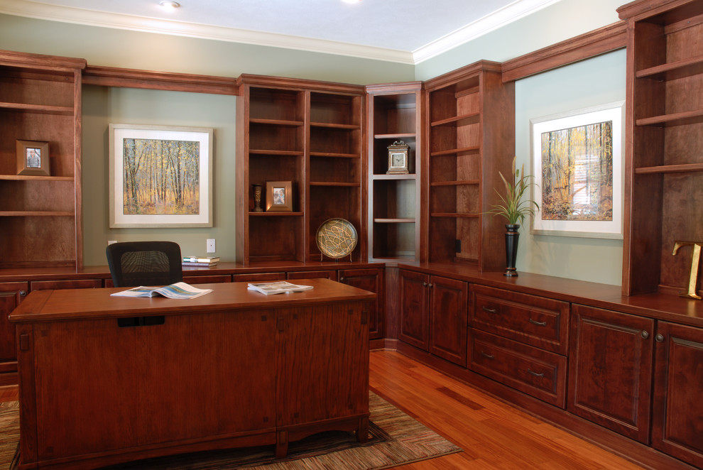 Klassisches Arbeitszimmer mit Arbeitsplatz, grüner Wandfarbe, braunem Holzboden und freistehendem Schreibtisch in Grand Rapids