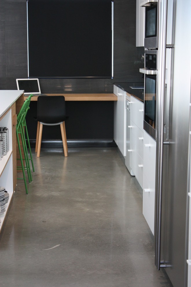 Пример оригинального дизайна: кабинет с черными стенами, бетонным полом и встроенным рабочим столом