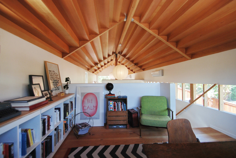 This is an example of a medium sized contemporary home office in Los Angeles with white walls, medium hardwood flooring, no fireplace, a freestanding desk and brown floors.