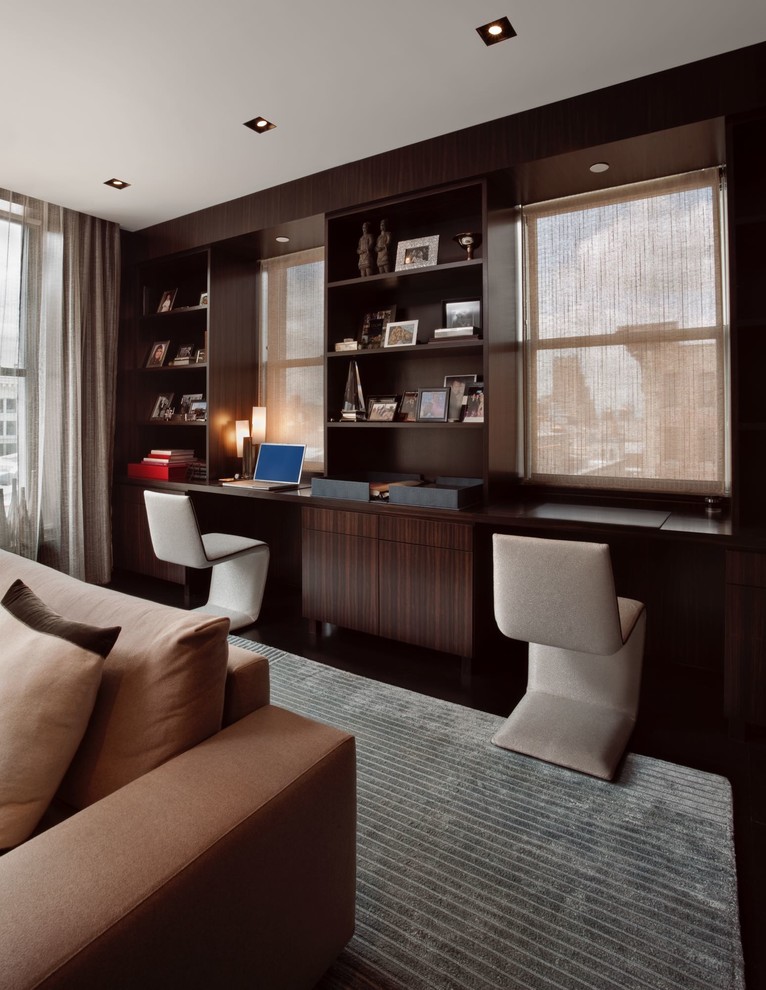 Ejemplo de despacho minimalista pequeño con paredes marrones, suelo de madera oscura, chimenea lineal, marco de chimenea de metal, escritorio empotrado y suelo marrón