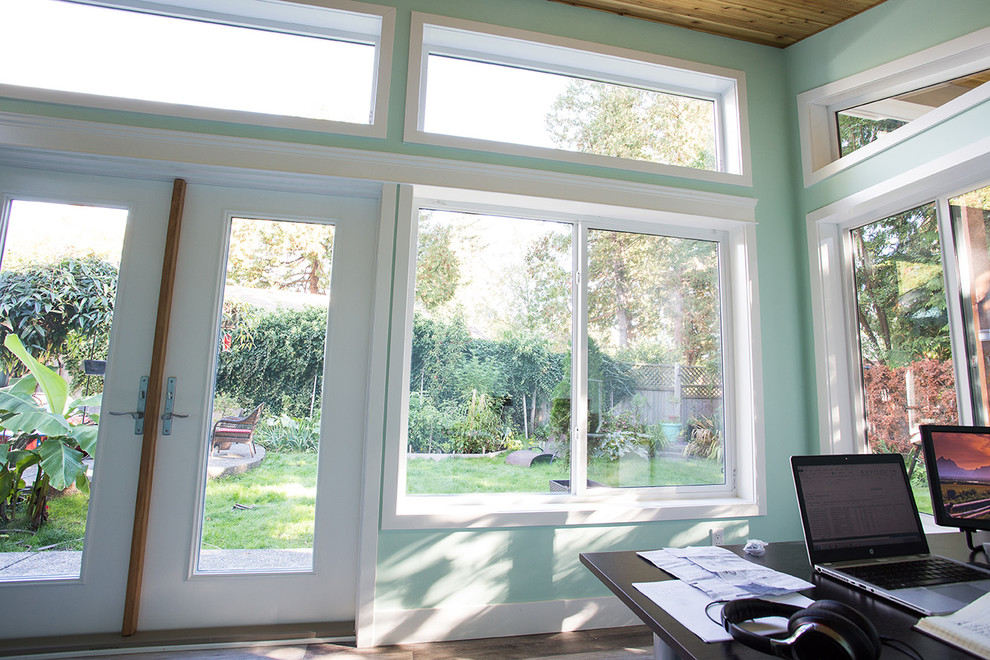 Ejemplo de despacho clásico de tamaño medio con paredes verdes, suelo de madera en tonos medios, escritorio independiente y suelo marrón