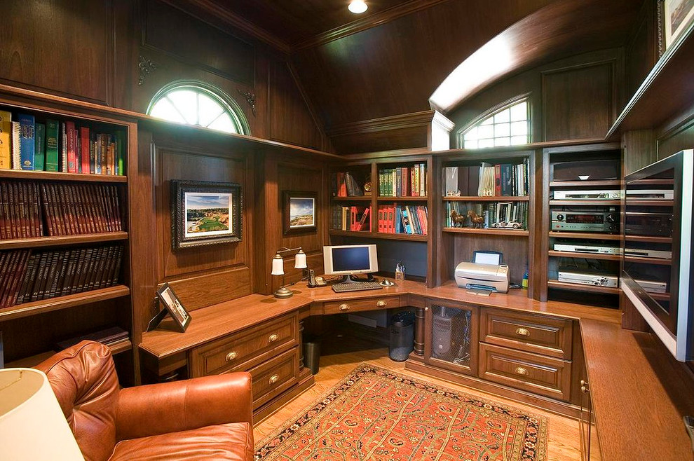 Modelo de despacho clásico de tamaño medio sin chimenea con suelo de madera clara, escritorio empotrado, paredes marrones y suelo marrón