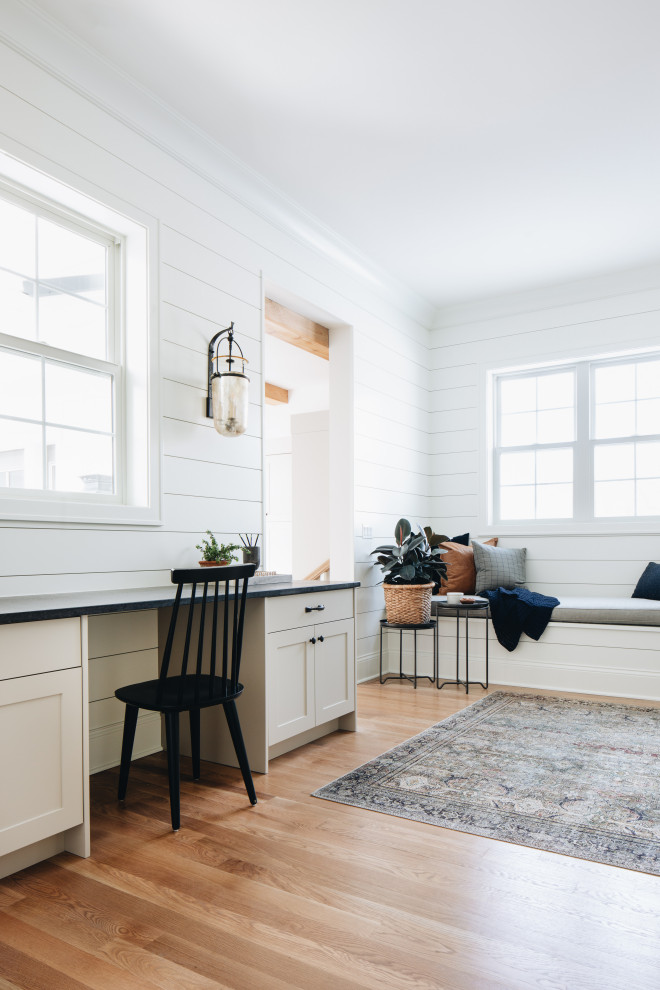 Example of a cottage built-in desk medium tone wood floor, brown floor and shiplap wall study room design in Chicago with white walls and no fireplace