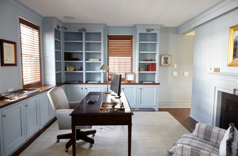 Foto på ett vintage arbetsrum, med ett bibliotek, blå väggar, en standard öppen spis och ett fristående skrivbord