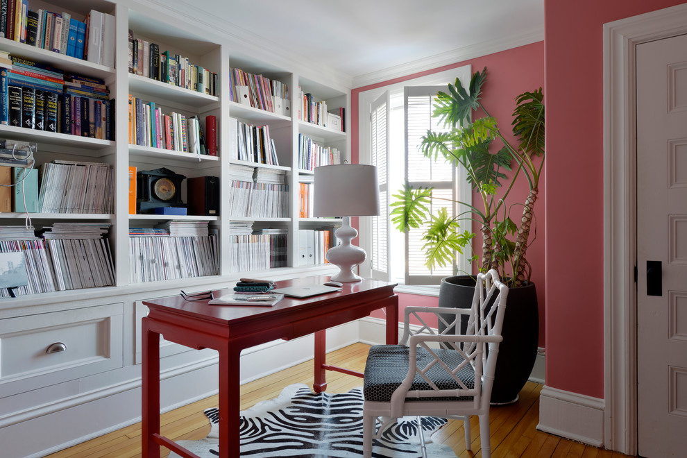 Inredning av ett klassiskt stort arbetsrum, med rosa väggar, ljust trägolv, ett fristående skrivbord och ett bibliotek