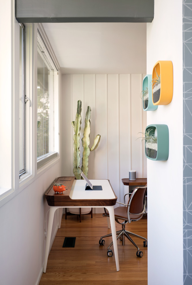 Imagen de despacho retro de tamaño medio sin chimenea con paredes blancas, suelo de madera en tonos medios, escritorio independiente y suelo marrón