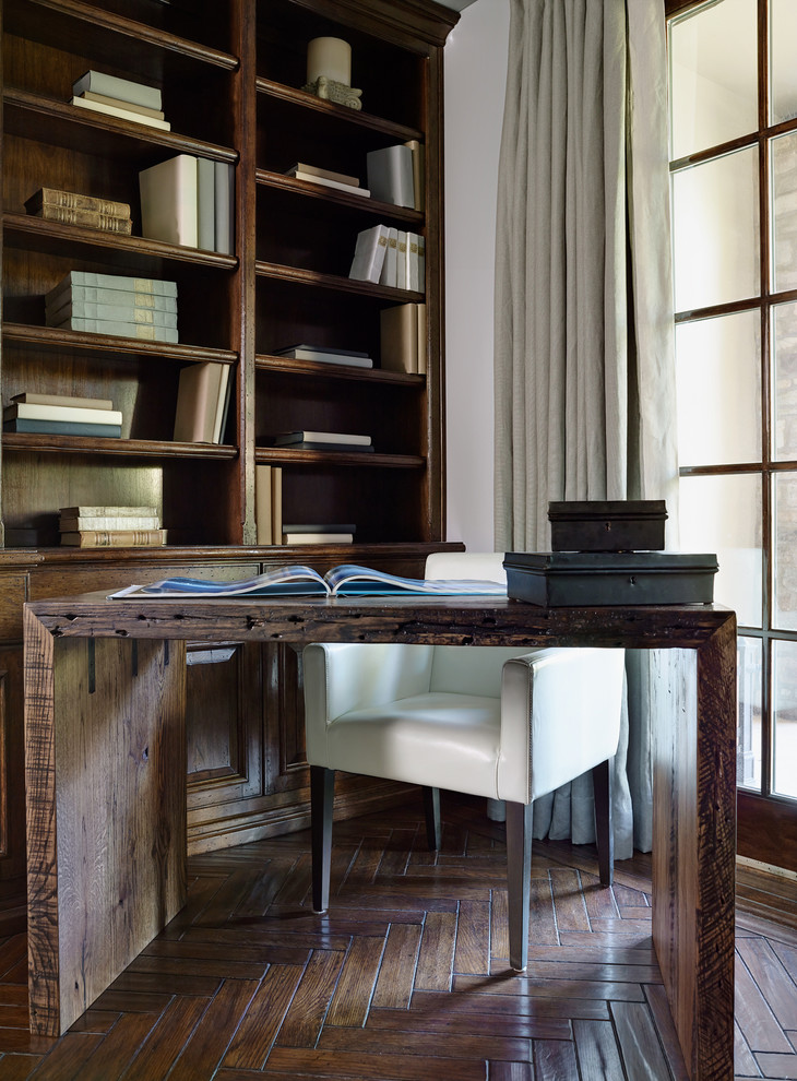 Imagen de despacho mediterráneo con paredes blancas, suelo de madera oscura y escritorio independiente
