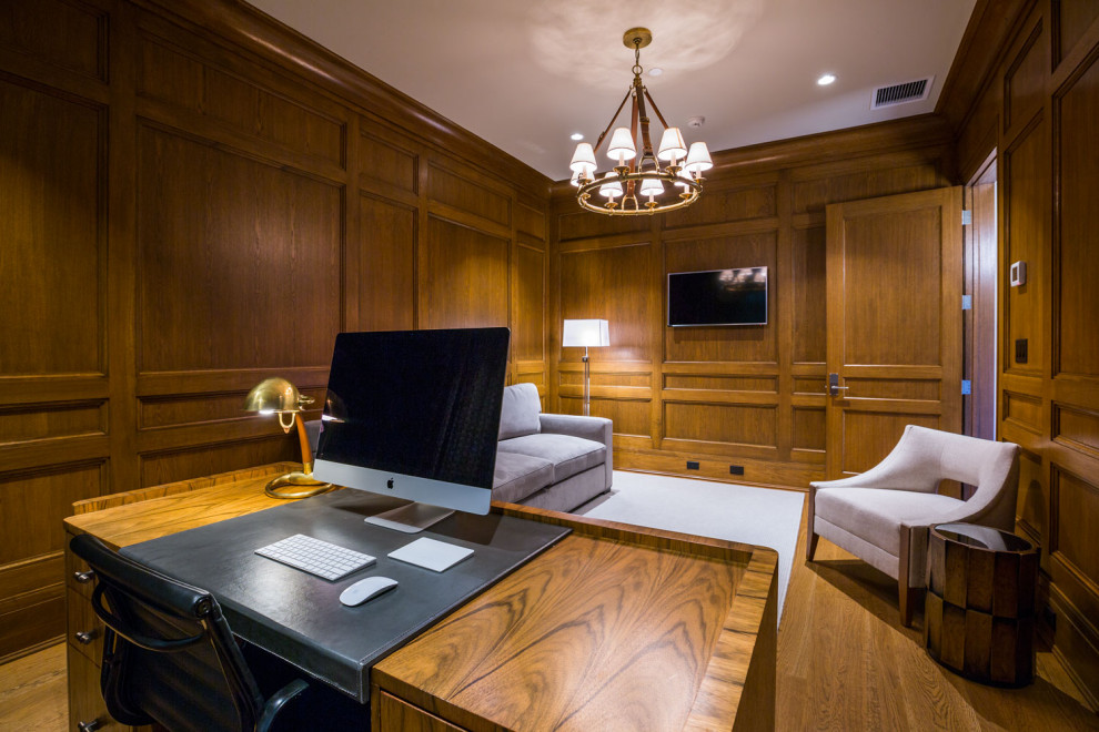 Großes Klassisches Arbeitszimmer mit Arbeitsplatz, brauner Wandfarbe, braunem Holzboden, freistehendem Schreibtisch, braunem Boden und Wandpaneelen in New York