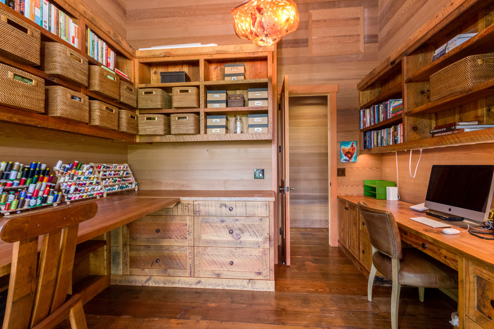 Cette image montre un grand bureau atelier chalet avec un sol en bois brun et un bureau intégré.