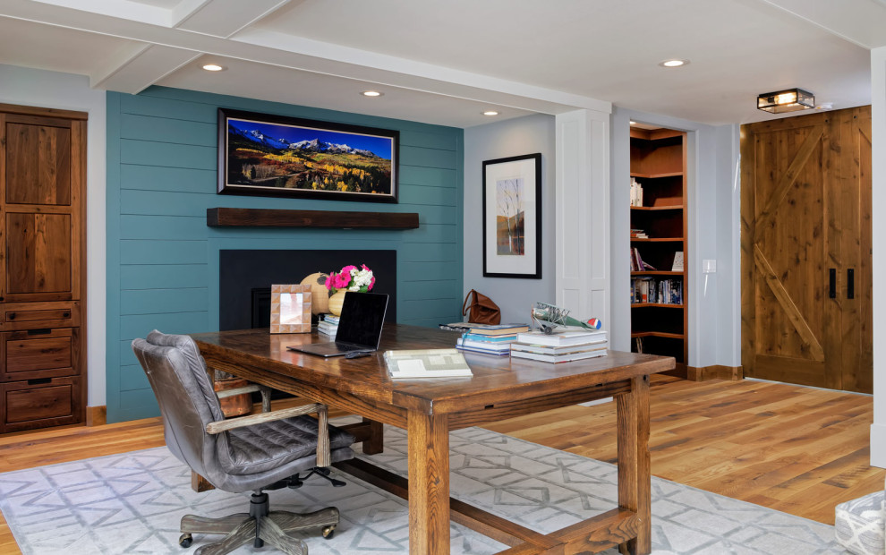 Diseño de estudio rural de tamaño medio sin chimenea con paredes azules, suelo de madera en tonos medios y escritorio independiente