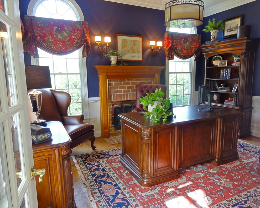 Idée de décoration pour un bureau tradition de taille moyenne avec un mur bleu, un sol en bois brun, une cheminée standard, un manteau de cheminée en brique et un bureau indépendant.