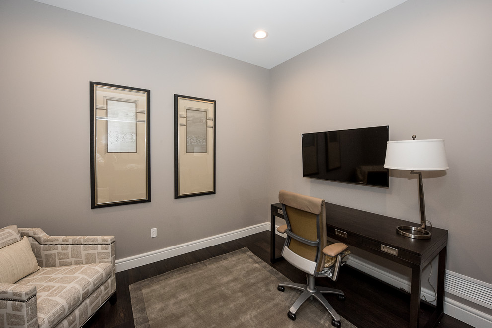 Cette image montre un bureau traditionnel avec un mur gris, parquet foncé, un bureau indépendant et un sol marron.