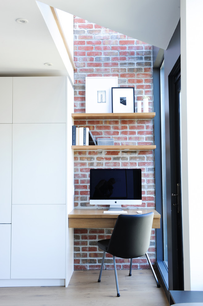Стильный дизайн: рабочее место в современном стиле с красными стенами, светлым паркетным полом и встроенным рабочим столом - последний тренд