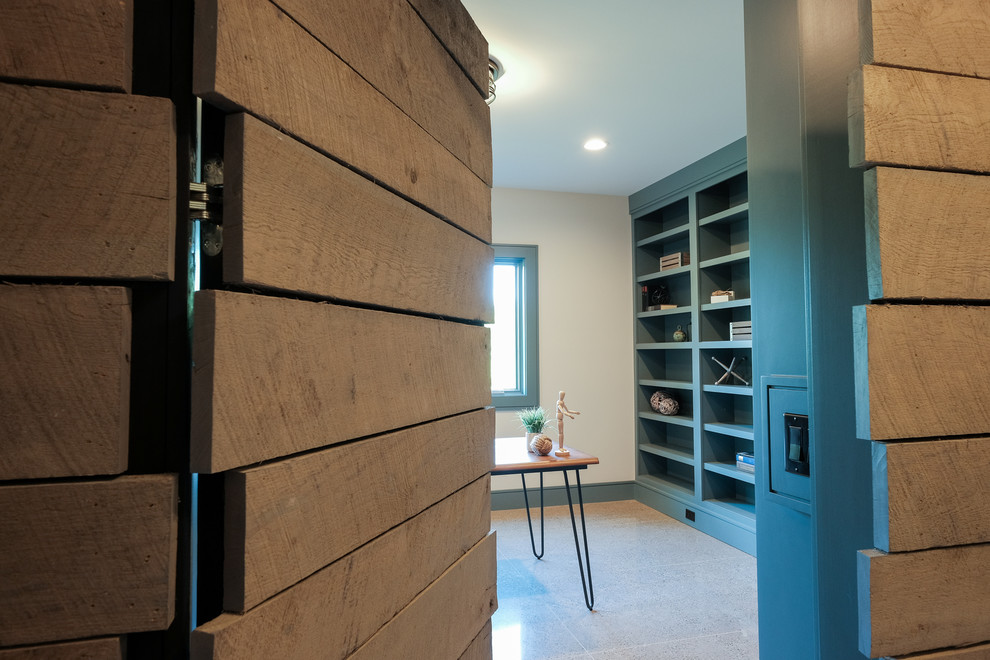 Diseño de despacho de estilo americano grande sin chimenea con paredes blancas, suelo de cemento, escritorio independiente y suelo gris