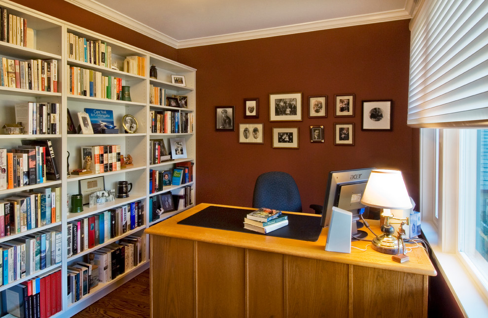 Foto de despacho clásico de tamaño medio sin chimenea con paredes rojas, suelo de madera en tonos medios y escritorio independiente