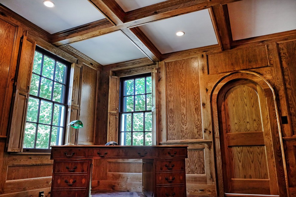 Inredning av ett klassiskt mellanstort arbetsrum, med bruna väggar, mörkt trägolv, ett fristående skrivbord och brunt golv