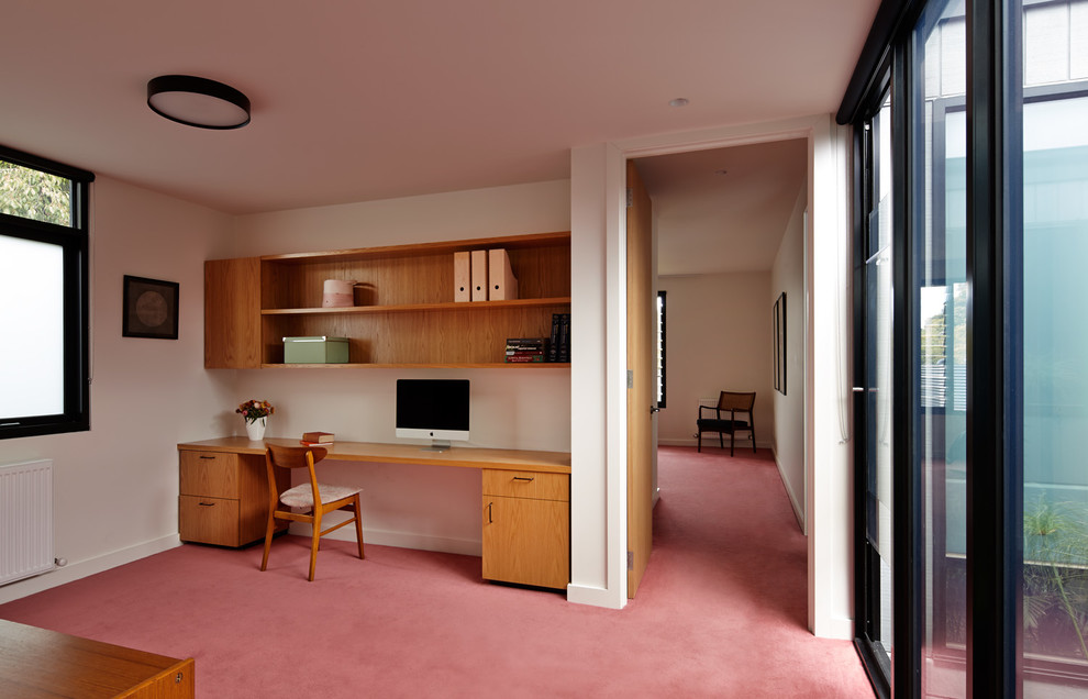 На фото: кабинет в современном стиле с встроенным рабочим столом, белыми стенами и ковровым покрытием
