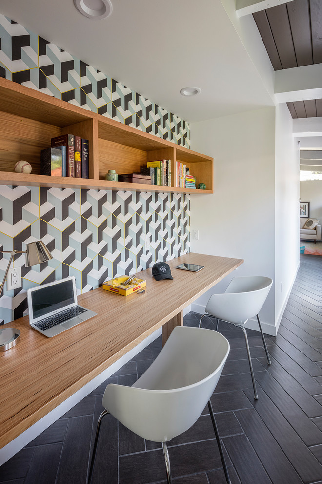 カンザスシティにあるミッドセンチュリースタイルのおしゃれなホームオフィス・書斎 (マルチカラーの壁、造り付け机、茶色い床) の写真
