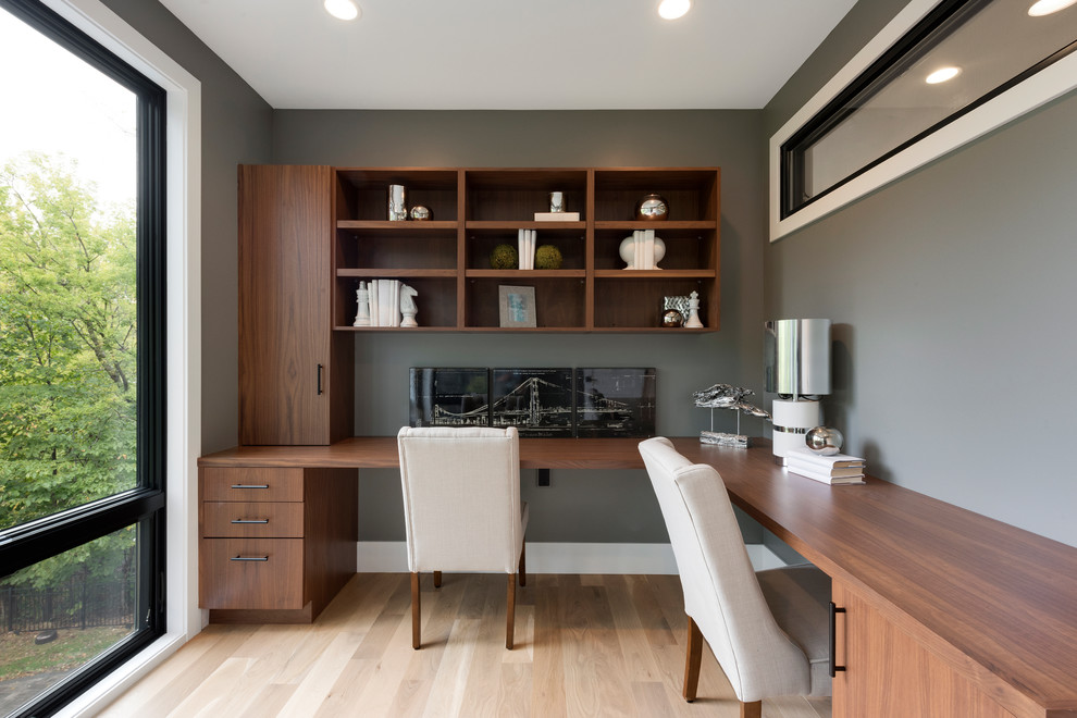 Imagen de despacho moderno pequeño con paredes grises, suelo de madera clara y escritorio empotrado