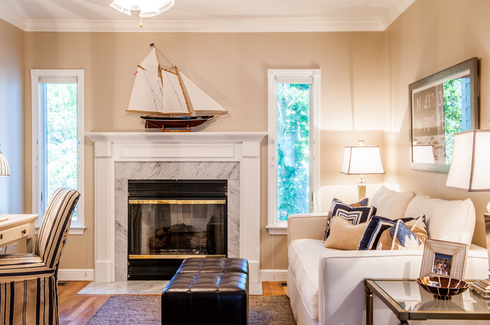 This is an example of a medium sized nautical study in Boston with beige walls, medium hardwood flooring, a standard fireplace, a tiled fireplace surround, a freestanding desk and brown floors.