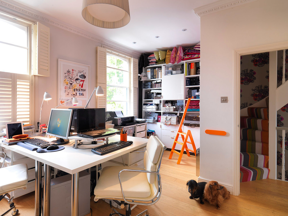 Kleines Modernes Arbeitszimmer ohne Kamin mit Arbeitsplatz, weißer Wandfarbe, braunem Holzboden und freistehendem Schreibtisch in London