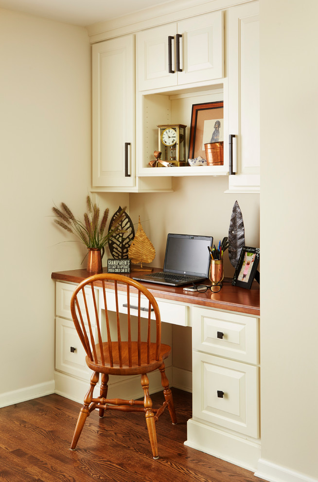 Foto de despacho tradicional con paredes beige, suelo de madera en tonos medios y escritorio empotrado