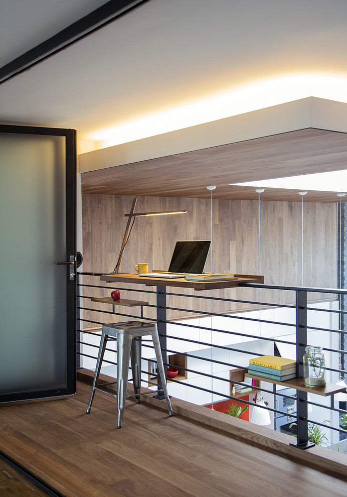Cette photo montre un petit bureau tendance avec un sol en bois brun et un bureau intégré.