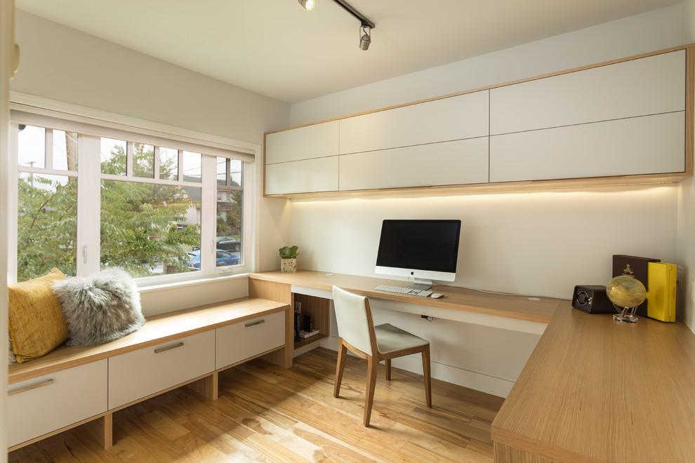 Medium sized contemporary study in Vancouver with white walls, light hardwood flooring, a built-in desk and brown floors.