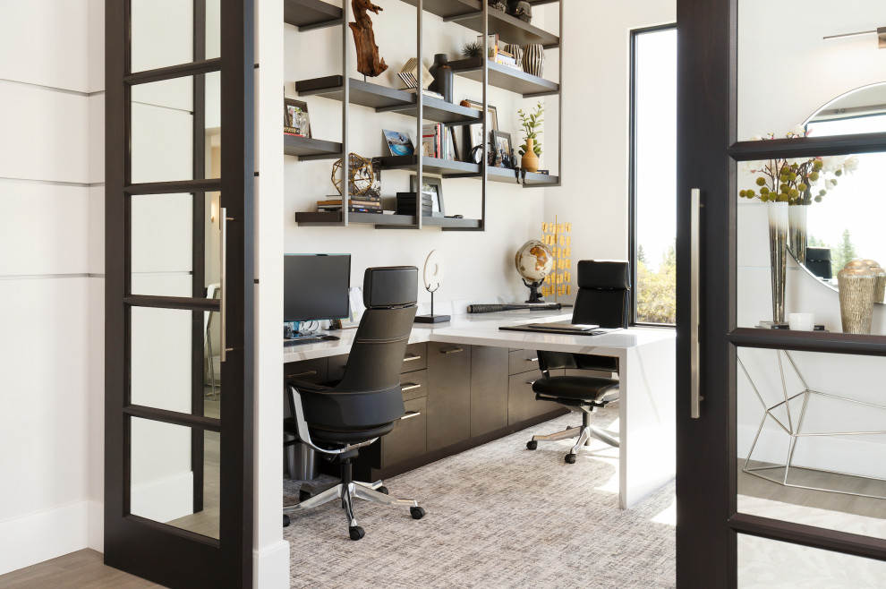 На фото: кабинет в современном стиле с белыми стенами, ковровым покрытием, встроенным рабочим столом и серым полом с