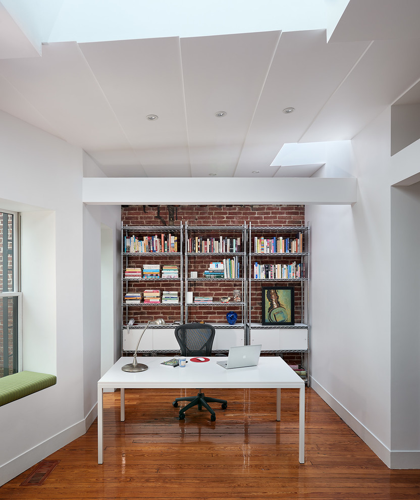 Diseño de despacho contemporáneo sin chimenea con paredes blancas, suelo de madera en tonos medios y escritorio independiente