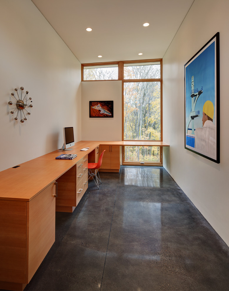 This is an example of a medium sized contemporary study in Milwaukee with white walls, concrete flooring, no fireplace and a built-in desk.