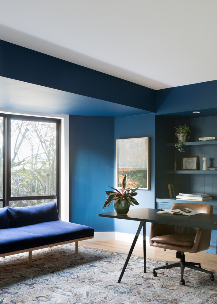 Foto de despacho escandinavo grande sin chimenea con paredes azules, suelo de madera clara, escritorio independiente y suelo marrón