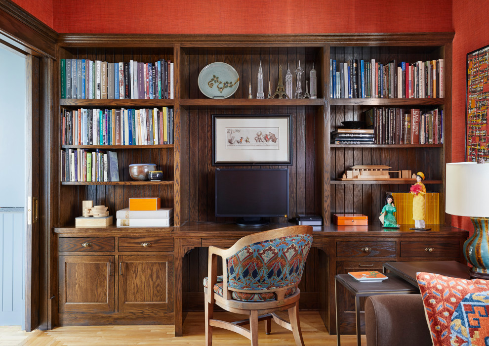 На фото: домашняя библиотека в стиле кантри с красными стенами, светлым паркетным полом и встроенным рабочим столом без камина с