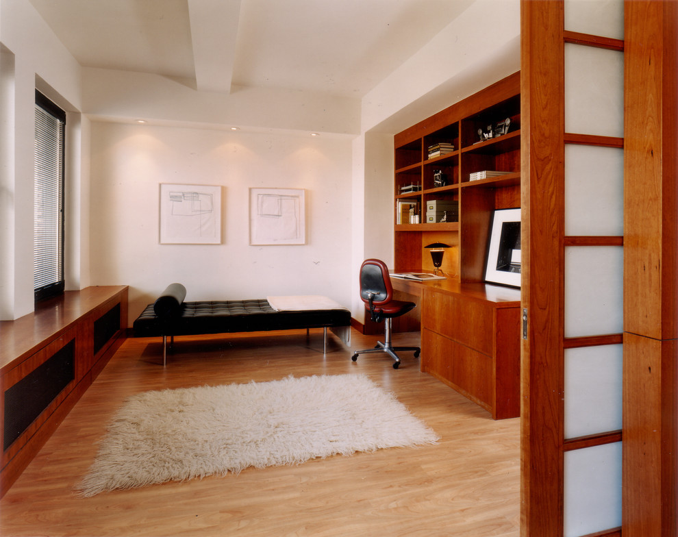 Immagine di uno studio minimal con pareti bianche, parquet chiaro e scrivania incassata
