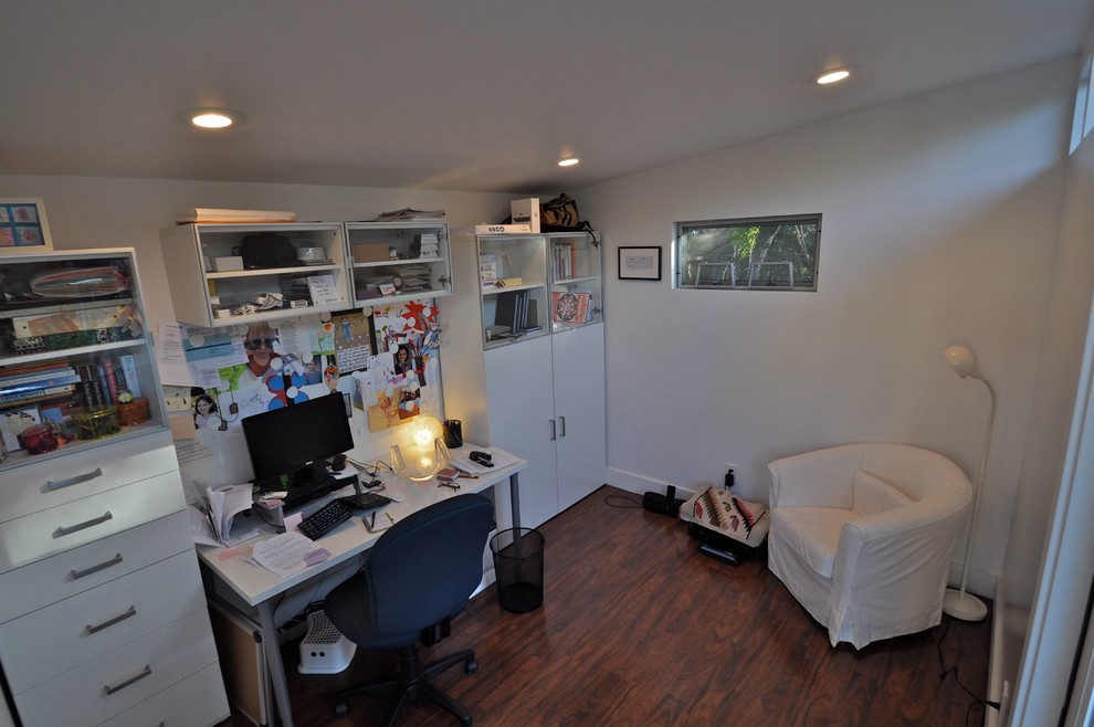 Esempio di un ampio ufficio moderno con pareti bianche, pavimento in laminato e scrivania autoportante